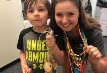 camp counselor with camper doing crafts