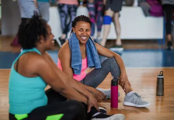 Two women smile at each other as they attend an exercise class.