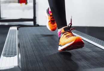 A woman wearing orange shoes running on a treadmill.