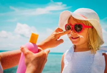 adult putting sunscreen on childs face