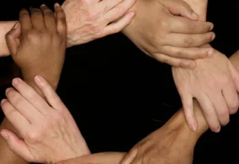 A series of hands clasped together in a circle.