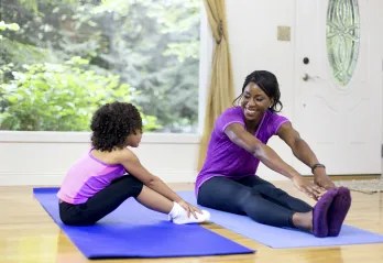 A mother and daughter stretching together.