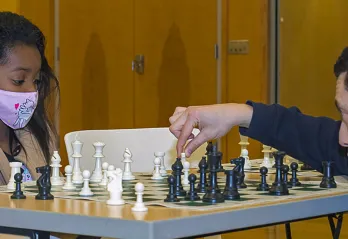 Grandmaster Gabriel Flom plays chess with kids at Hayes-Taylor YMCA.