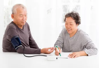 A senior couple monitoring their blood pressure at home.