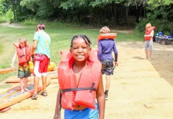 Kid with an orange lifejacket at summer camp.