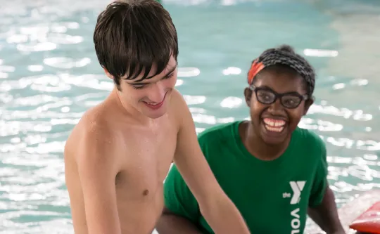 A volunteer helps a swim lesson participant.