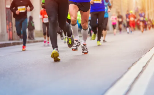 A group of people running a race on a paved road.