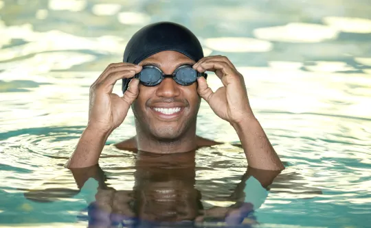 A man wearing swimming goggles while in a pool.