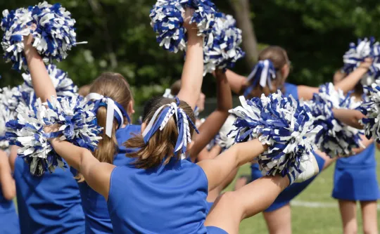 A group of cheerleaders wearing blue uniforms.