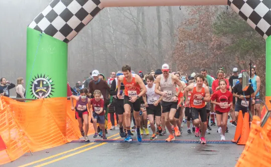 The starting line at the Ragsdale YMCA's Reindeer Romp road race. A crowd of runners are running toward the camera.