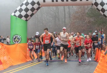 The Reindeer Romp starting line. A crowd of people wearing running gear are running toward the camera as the race starts.