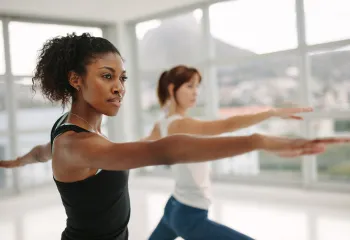 Two women in a yoga class holding a yoga pose and concentrating.