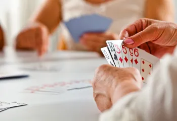 A close up photo of a senior woman's hand while she plays a card game.