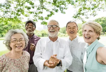 A diverse group of seniors standing outdoors together and laughing.