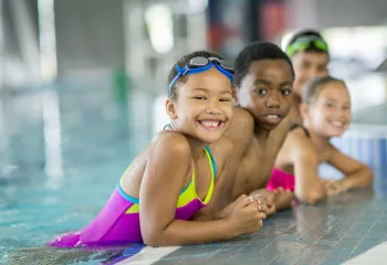 A group of young children swimming.