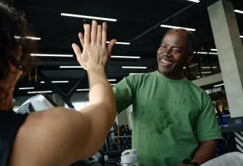 Man working out in the gym giving a high five to a woman
