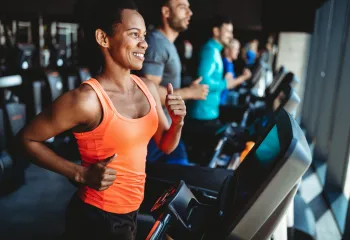 A woman running on a treadmill at the gym.