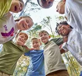 A group of kids smiling and laughing as they play together outside.