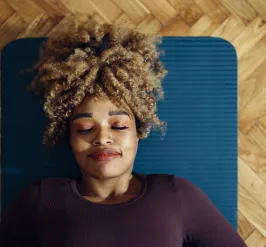 A woman relaxing in a yoga pose on a yoga mat. Her eyes are shut.