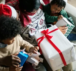 Family opening Christmas presents on couch