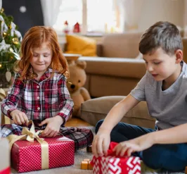 young boy and girl opening Christmas presents in living room