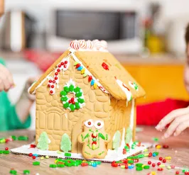 Two young boys build a gingerbread house together.