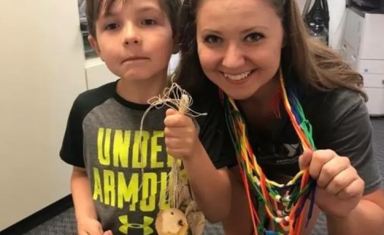 camp counselor with camper doing crafts