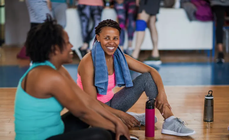 Two women smile at each other as they attend an exercise class.