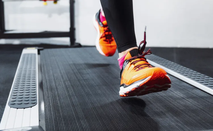 A woman wearing orange shoes running on a treadmill.