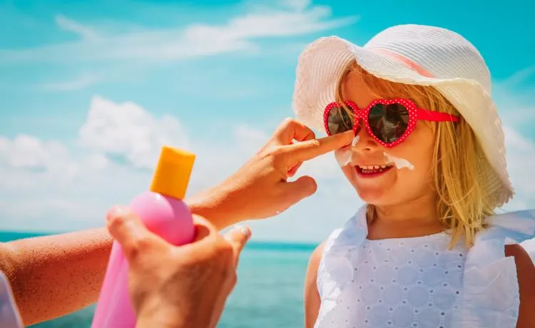 adult putting sunscreen on childs face