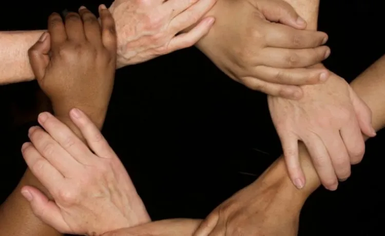 A series of hands clasped together in a circle.