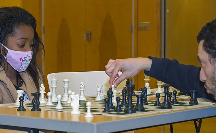 Grandmaster Gabriel Flom plays chess with kids at Hayes-Taylor YMCA.