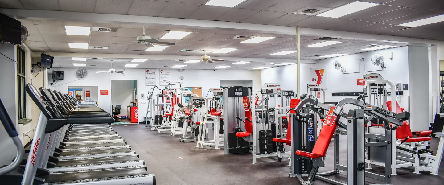 A photo of the Stoney Creek YMCA's fitness room. There are rows of treadmills and other exercise machines.