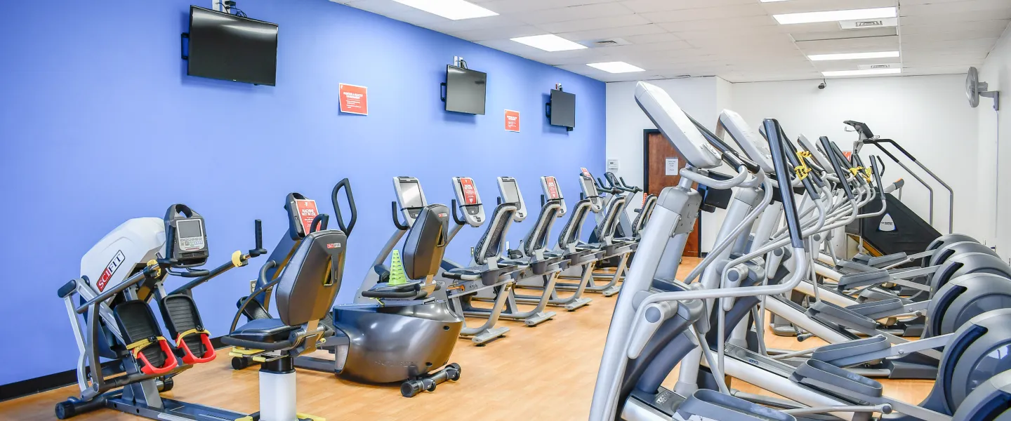 A photo of an exercise room in the Stoney Creek YMCA. There are rows of exercise machines.