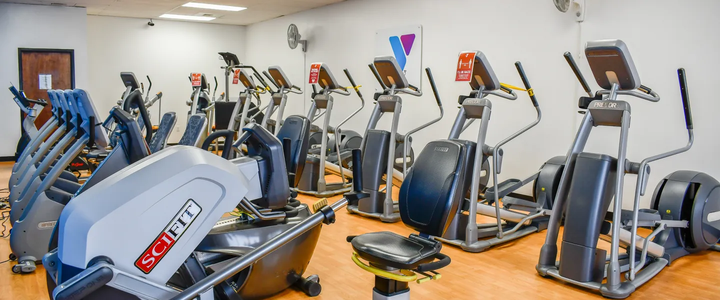 A photo of an exercise room in the Stoney Creek YMCA. There are rows of exercise machines.