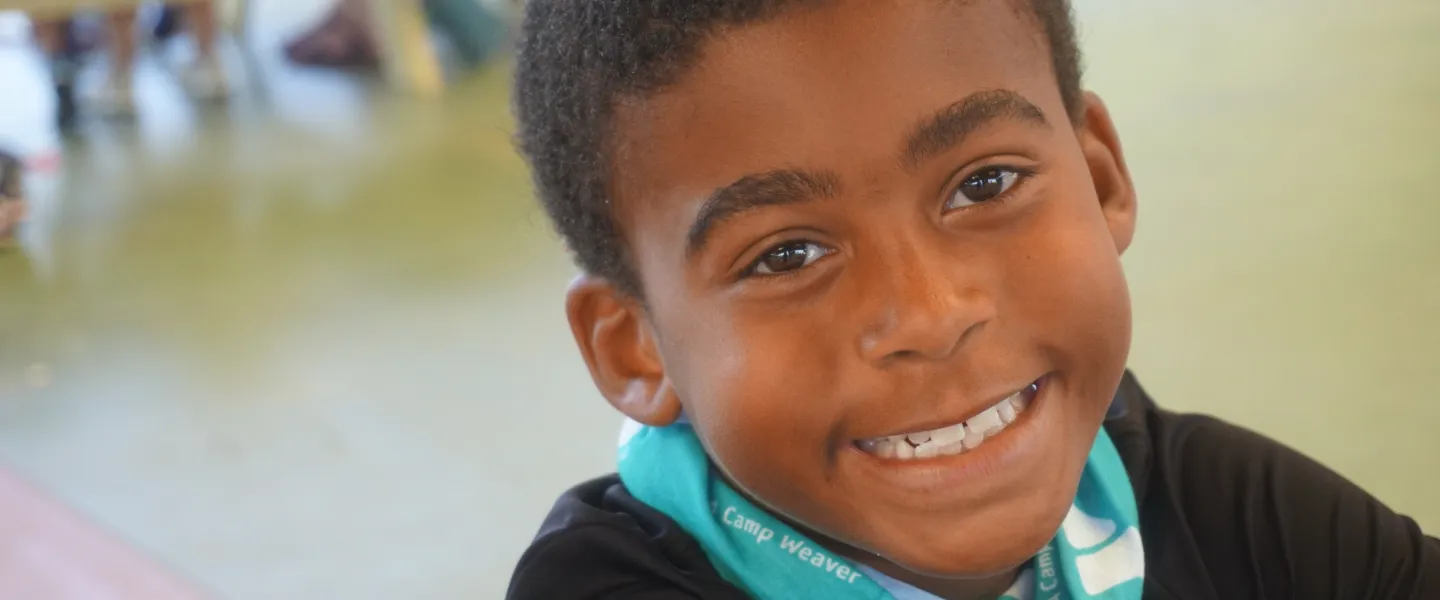 A boy at YMCA Camp Weaver smiles into the camera.