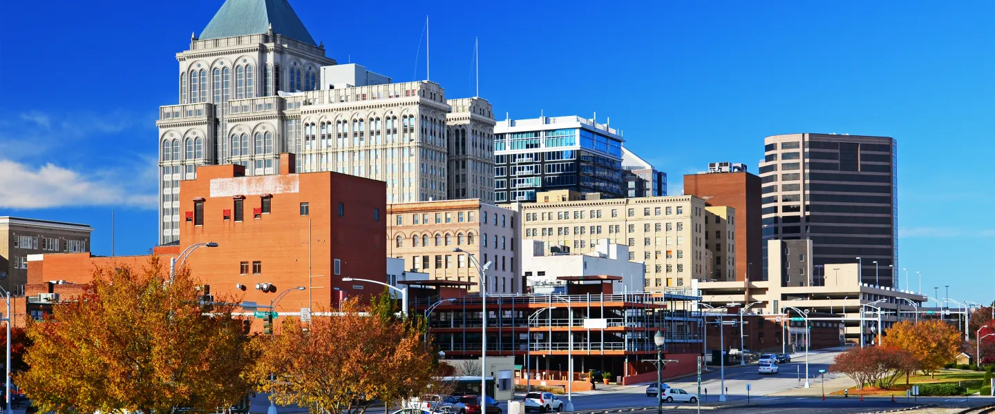 Greensboro, North Carolina during autumn. There are trees with orange leaves and the city skyline.