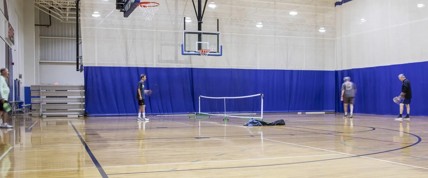 People playing pickleball in gym. 