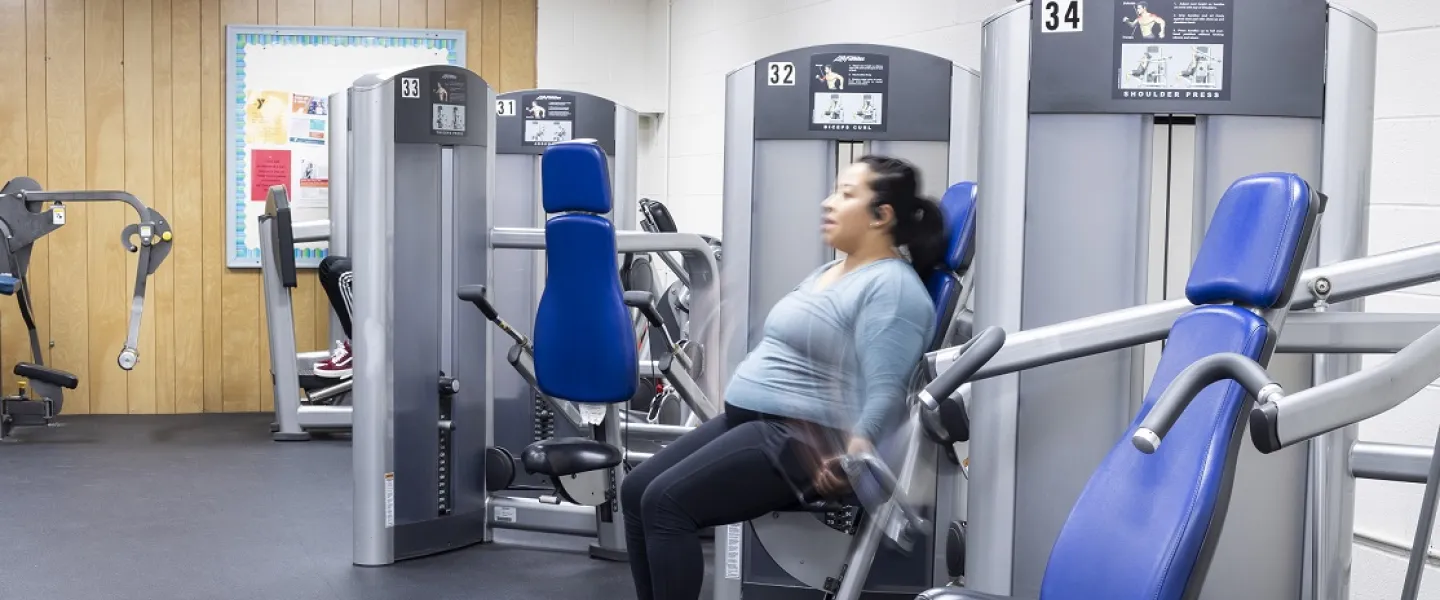 A woman working out using a weightlifting machine at the Eden YMCA.