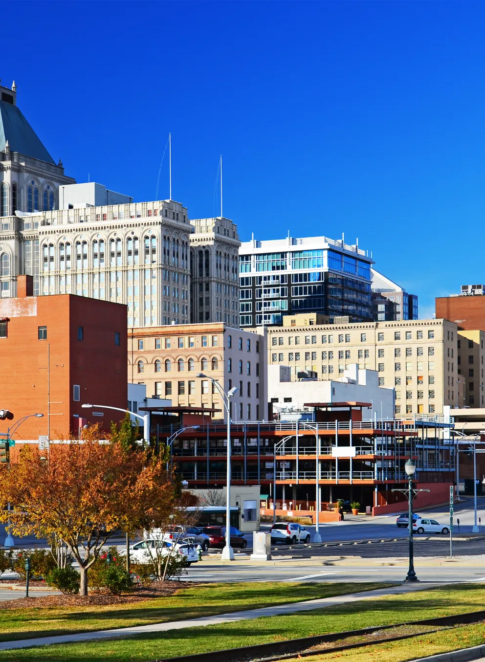 Greensboro, North Carolina during autumn. There are trees with orange leaves and the city skyline.