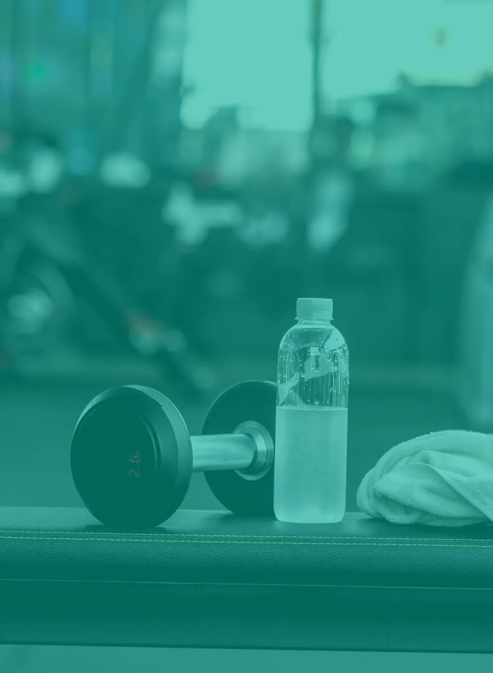 A weight bench in a fitness area. A white towel, a half-filled waterbottle, and a hand weight sit on top of the bench.