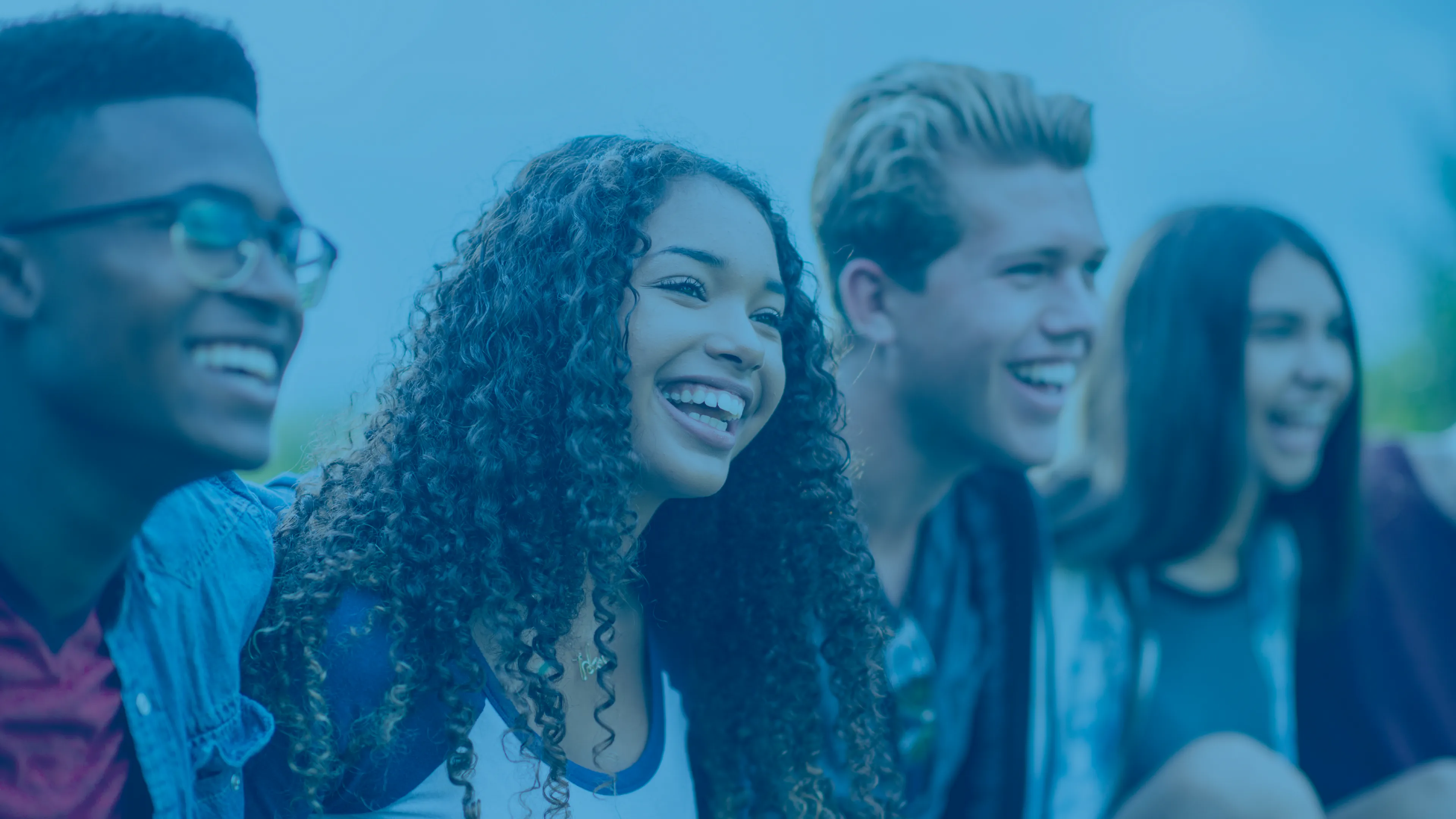 A group of four diverse teens smiling and laughing together.
