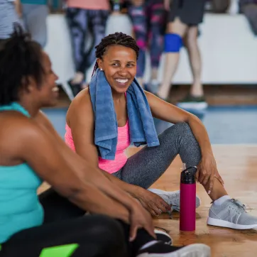 Two women smile at each other as they attend an exercise class.