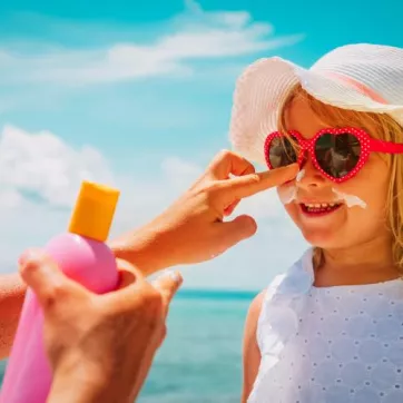 adult putting sunscreen on childs face