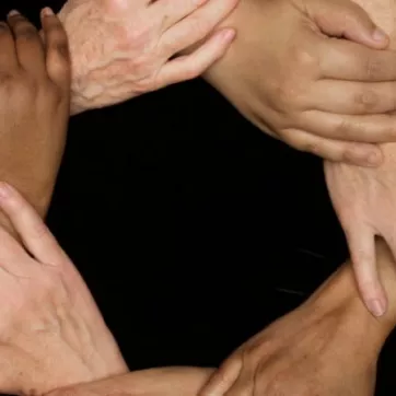 A series of hands clasped together in a circle.