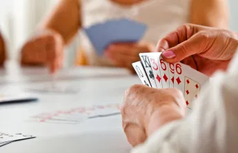 A close up photo of a senior woman's hand while she plays a card game.