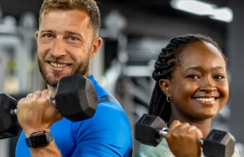 Man and woman side by side holding weights in their hand