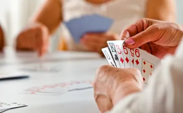 A close up photo of a senior woman's hand while she plays a card game.