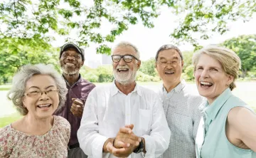 A diverse group of seniors standing outdoors together and laughing.